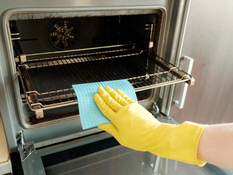 Hand cleaning oven racks with a microfiber cloth.